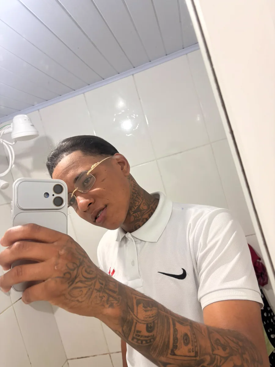 Souza, streamer da Fusion, de óculos e camisa polo branca, em selfie no espelho